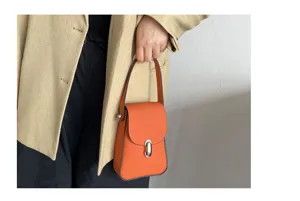 Orange leather mini phone bag detail, stylish vertical shape with metal lock accent.