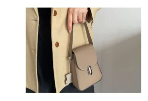 Close-up detail of the genuine leather phone bag handle and metal lock clasp in taupe.