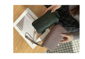 Detailaufnahme einer mehrlagigen Damen-Kupplungsgeldbeutel aus Kroko-Leder mit Handschlaufe.