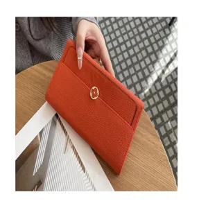 Detail shot of orange leather long wallet for women, genuine cowhide purse clasp design.