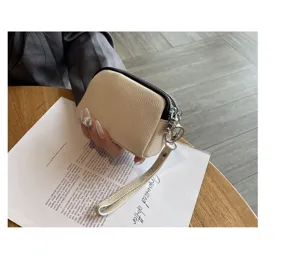 Detailed view of a mini beige leather coin purse with double zippers and wrist strap for women.