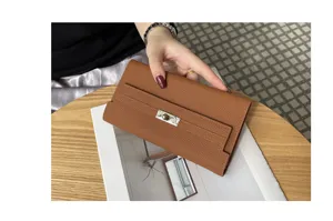 Detail view of the brown leather long wallet featuring a classic metal lock closure.