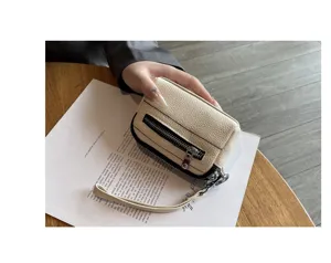 Detail view of mini leather coin purse with double zippers and wrist strap for women.