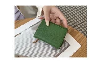 Green genuine leather tri-fold mini wallet detail, compact size with coin pocket storage.