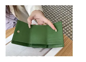 Detailed view of green genuine leather trifold mini wallet interior structure and pocket design.