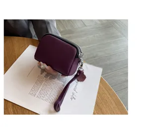 Compact genuine leather mini coin purse with double zippers and wrist strap for women.