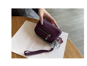 Close-up detail of genuine leather mini coin purse with double zipper and wrist strap.