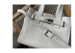 Sac cabas bandoulière pour femme en cuir blanc avec poignée et fermeture à tourniquet.