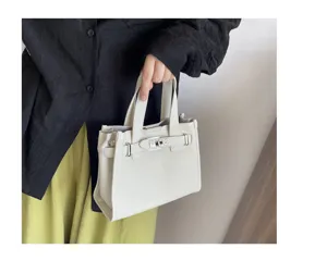 Petit sac cabas en cuir blanc élégant avec fermeture à tourniquet et poignée.
