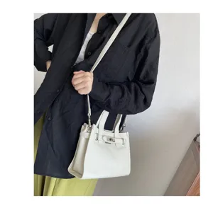 Sac à main bandoulière en cuir véritable pour femme avec serrure métallique classique.