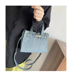 Sac à bandoulière en cuir bleu clair pour femme, style kelly classique avec fermoir métallique.