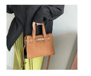Détail de sac Kelly en cuir marron montrant un design structuré, serrure et poignées.