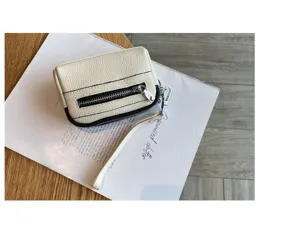 Detail shot of white leather mini coin purse with double zippers and wrist strap.