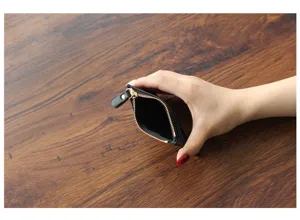Detail shot of a black leather mini zipper coin purse showing interior structure on wooden table.