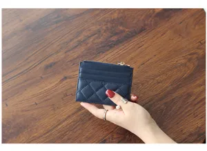 Close-up detail shot of the navy blue quilted leather cardholder featuring zipper and slots.