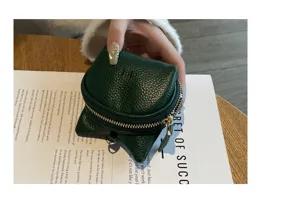 Close-up detail of a dark green leather coin purse with cute cat ears and metal zipper.