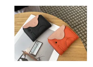 Detail shot of genuine leather elephant card holder in black and orange with cute flap design.