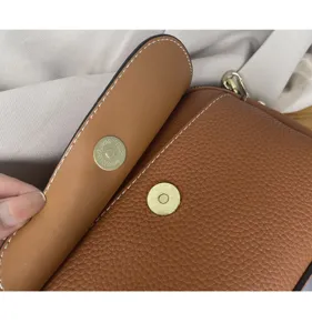Brown leather crossbody bag detail showing fine stitching and durable magnetic snap closure.