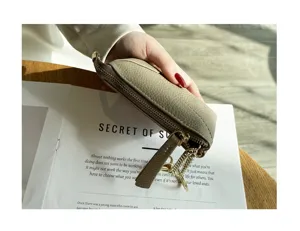 Detailed view of genuine leather coin purse with metal zipper and key chain on wooden desk.