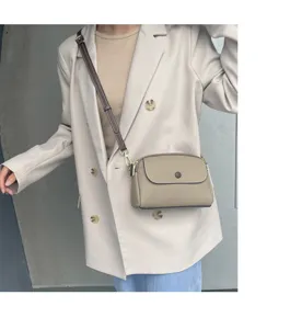 Detail shot of a trendy genuine leather crossbody bag worn by model, showing exquisite hardware.