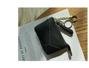 Detailed view of a black genuine leather coin purse with golden chain and zipper closure.