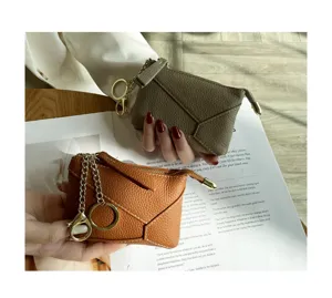 Detail shot of mini leather coin purses with geometric stitching, gold chains and key rings.