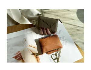 Genuine leather coin purse and key case detail shot, soft cowhide material with zipper and chain.