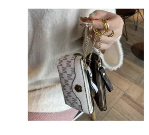 Detailed view of mini coin purse with monogram print, metal chain and floral charm design.