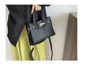 Sac à main bandoulière en cuir noir avec serrure métallique classique et lanières.