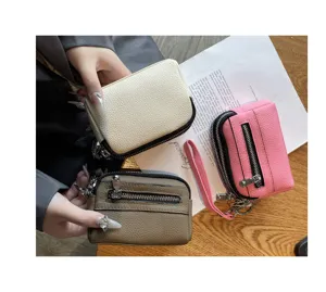 Close-up detail of mini genuine leather coin purses with double zippers and wristlet strap.