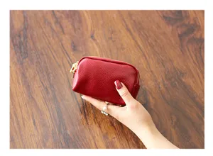 Detailaufnahme einer kompakten roten Echtleder-Münztasche mit mehreren Reißverschlussfächern.