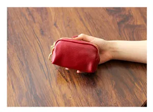 Nahaufnahme einer kompakten roten Leder-Muenztasche mit drei Reissverschluessen und Ring.