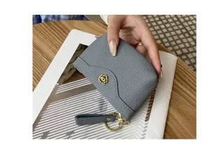 Closeup gray leather coin purse with chic floral metal button, compact card holder key ring.