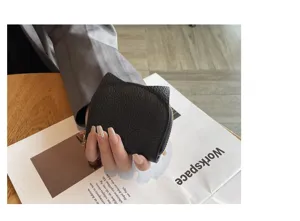 Detailed close-up shot of the black leather cat ear card holder showing zipper and texture.