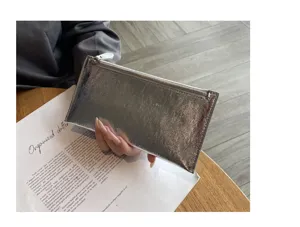 Echt lederen portemonnee detail, zilveren metallic koeienhuid afwerking, slanke ritsvak ontwerp.