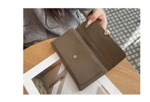 Detail shot of a brown genuine leather long wallet showing grain texture and metal clasp.
