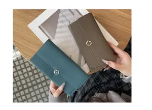 Classic clover metal clasp detail on premium leather long wallet, elegant hand-held lifestyle view.