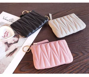 Detailed view of mini quilted leather coin purses with zipper and key ring in three colors.