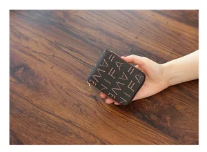 Detalle de monedero monograma marrón con diseño compacto de cremallera y tarjetero práctico.