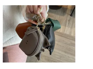 Detail view of mini genuine leather coin purses in multiple colors attached to a sleek metal keychain.