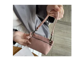 Detail close-up shot of pink leather mini coin purse featuring wrist strap and zipper closure.