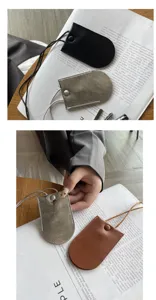 Primo piano della custodia per chiavi da collo in vera pelle e del grazioso mini ciondolo per borsa.