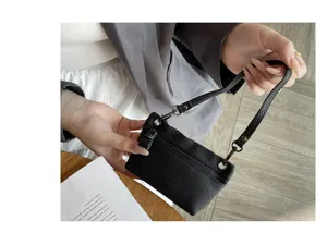Close-up detail shot of black genuine leather mini coin purse with wrist strap and metal zipper.