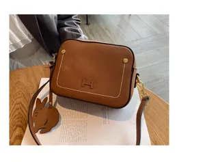 Stylish brown genuine leather shoulder bag, trendy crossbody camera bag with rabbit charm.