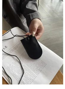 Primo piano dettagliato di una piccola custodia per chiavi in pelle nera con cordino e bottone.
