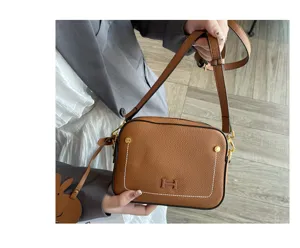 Brown leather crossbody camera bag with stylish front H logo detail and adjustable strap.