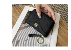 Black leather coin purse wallet with floral clasp, wrist strap and keychain. Detailed view.