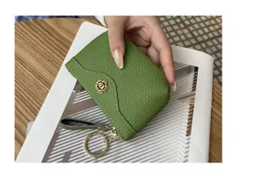 Detail shot of a green cowhide leather coin purse with flower button and keychain loop.