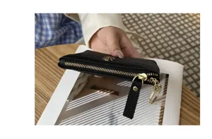 Detail view of women's genuine leather coin purse in black with chic floral metal accent.