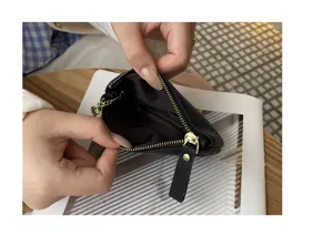 Detail shot showing interior and zipper of black leather coin purse, compact everyday accessory.
